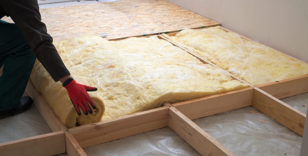 Worker laying down insulation in a home