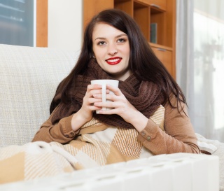 Woman in a blanket with a mug protected by smoke alarm