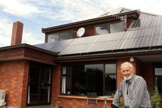 Michael proudly standing in front of his new solar panels on his home